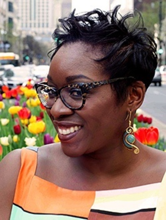 A portrait of Dr. Atuahene in front of a field of tulips in downtown Detroit